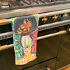 Towel with colorful art hanging on a stove.